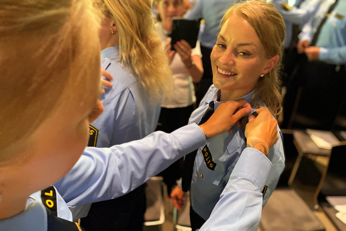 Ett fotografi som visar när de nyutbildade poliserna hjälper varandra med att byta axelklaffar.