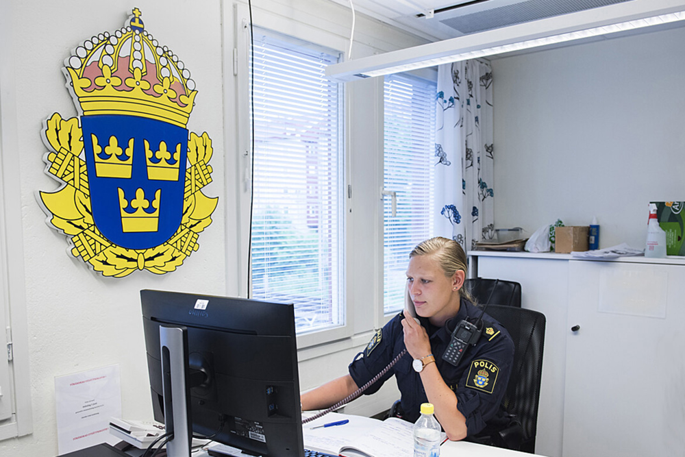 Polis i telefon vid ett skrivbord.
