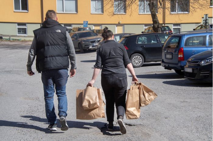 Två av spanarna går över en parkering och den ena bär flera papperskassar. Foto.