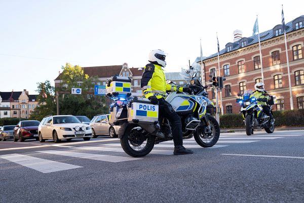 Två poliser på motorcyklar som har stannat trafiken vid ett trafikljus.