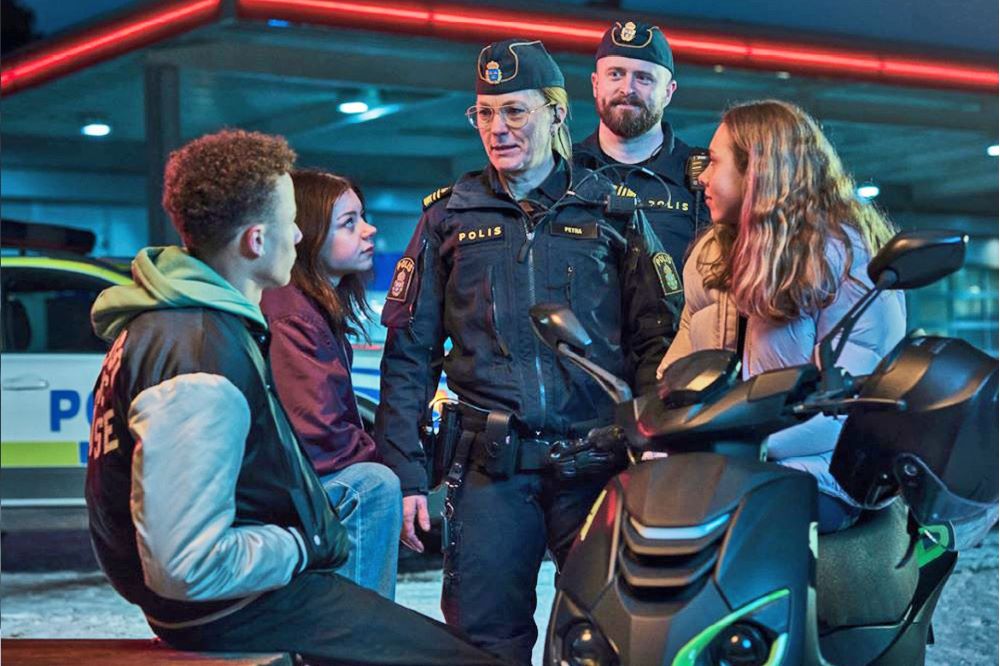 Skärmdump från filmen: Två poliser står och pratar med ungdomar