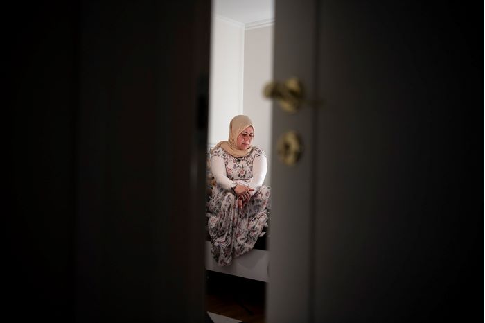 Foto på en kvinna som man ser genom en dörr på glänt.