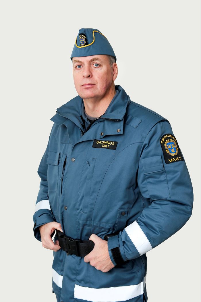Ordningsvakt i båtmössa och ytterjacka. Halvfigur.