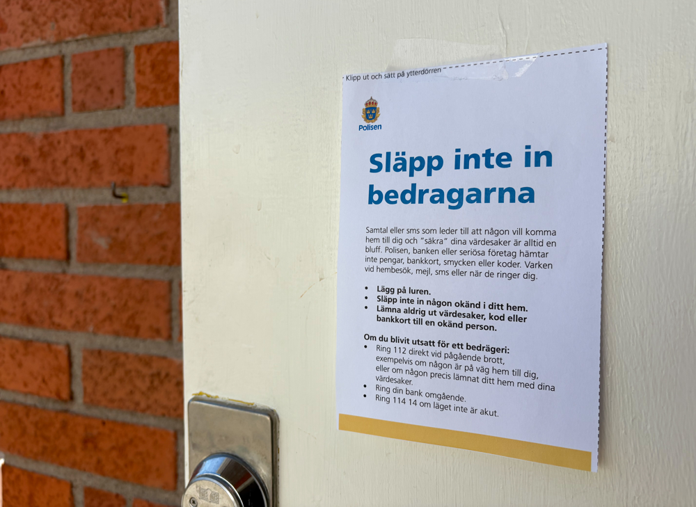 Lapp på en vit ytterdörr med texten "Släpp inte in bedragarna"
