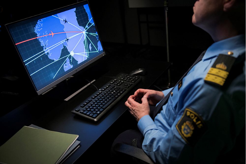 Polis i mörkt rum vid datornskärm