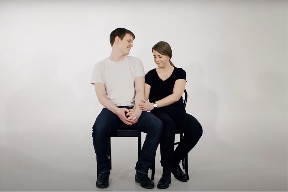 En kvinna och en man sitter på varsin stol och håller varandras händer.