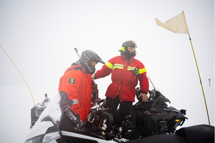 polis och fjällräddare vid skotrar i snöoväder på fjället