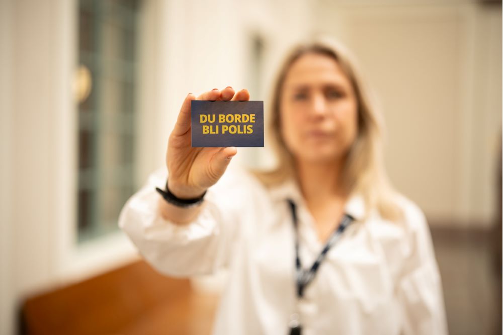 En person håller uppe ett kort som det står "du borde bli polis" på.