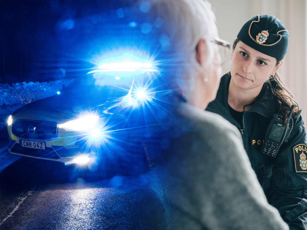 En blinkande polisbil och en polis som samtalar med en äldre kvinna. Kvinnan har ryggen emot.