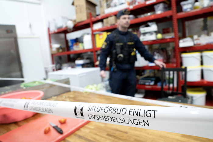 Polis i bakgrunden och en avspärrning med texten Salutförbud enligt livsmedelslagen