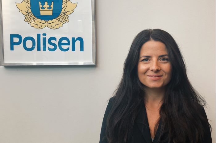 Lovisa mot en ljus vägg och tavla med polisvapnet på.