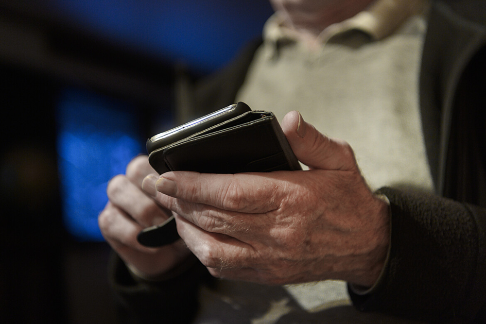 En närbild på telefon och två händer som hanterar den.