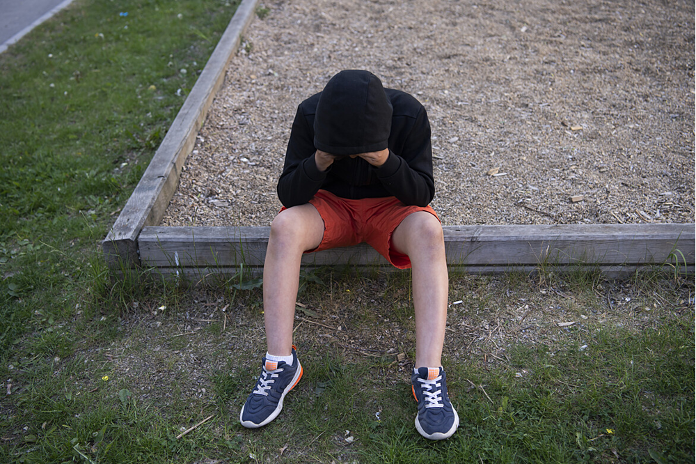 Pojke i kortbyxor sittande vid en sandlåda