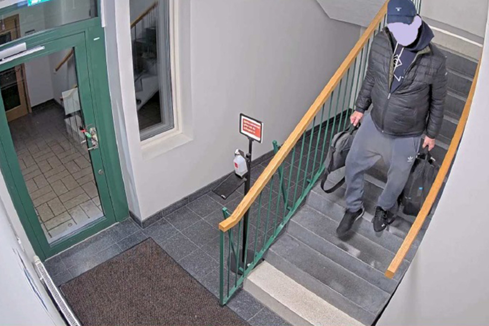 Man bär två väskor nerför trappa i trapphus.