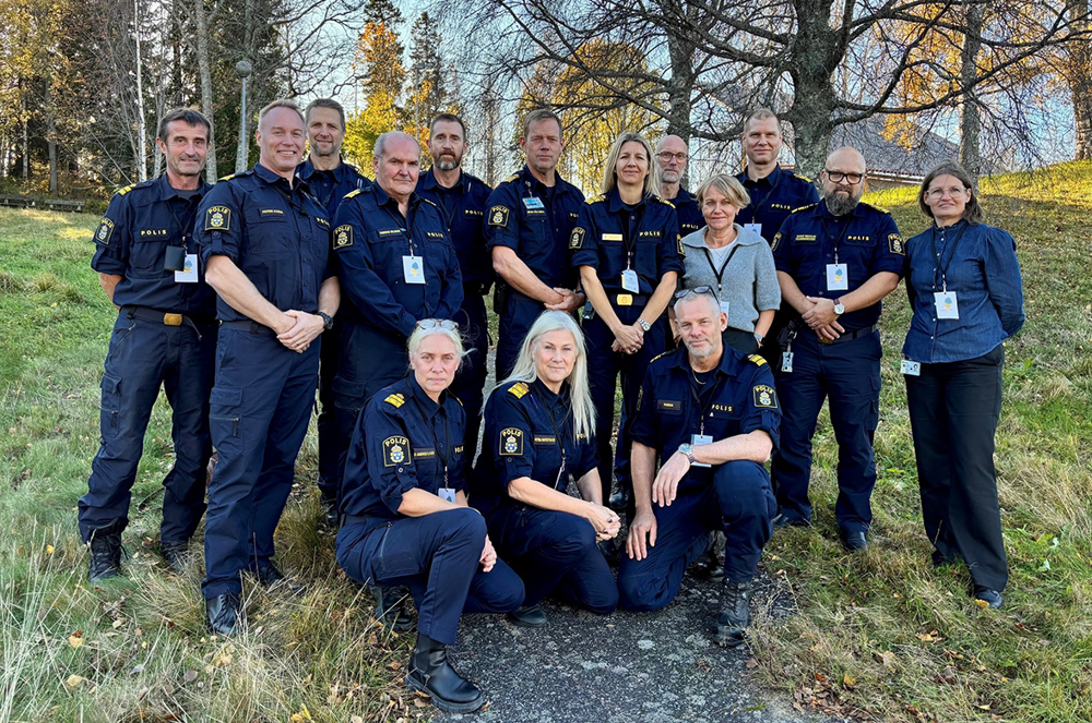 Gruppbild på 15 personer utomhus.