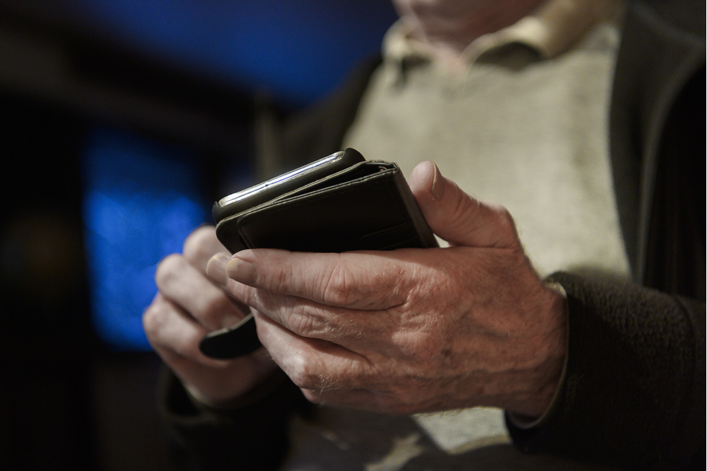 Äldre man som håller i mobiltelefon