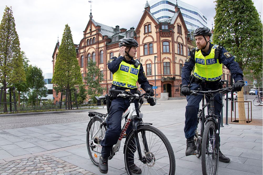Två cyklande poliser som står och pratar intill ett torg i Umeå