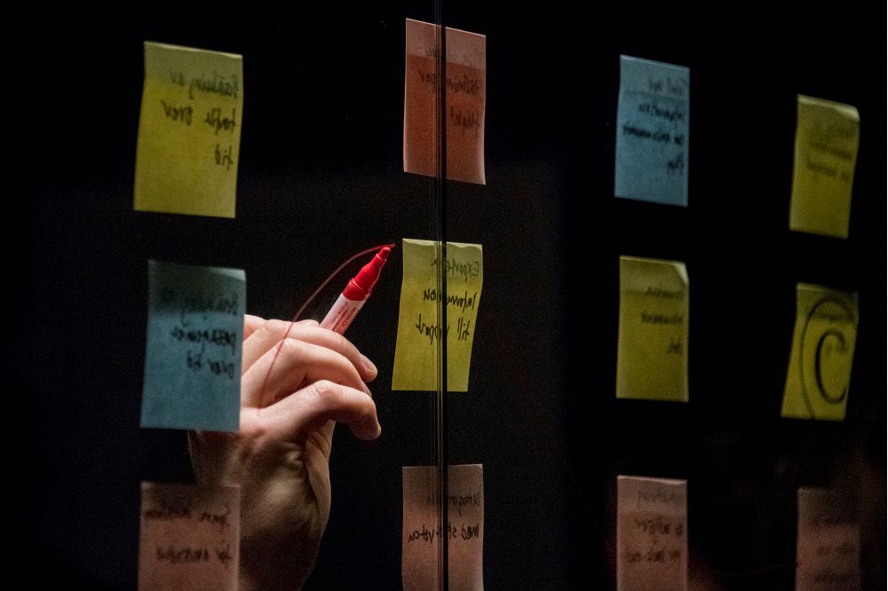 Person pekar på post-it-lappar på en glasvägg