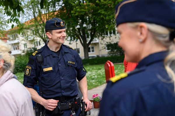 Polis utomhus i uniform som pratar med medborgare.