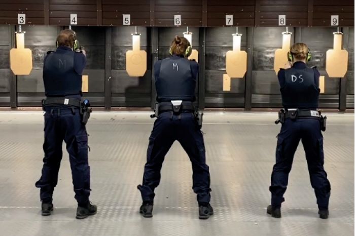 Bild på ryggarna på poliser som tränar skytte mot måltavlor.