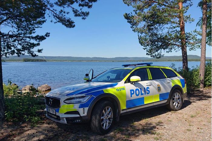 Polibil parkerad på berg med utsikt mot vatten.