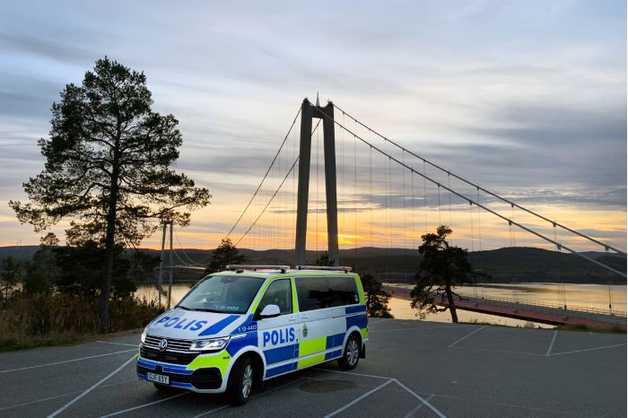 Polisbil med höga kusten bron i bakgrunden.