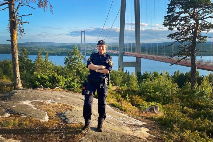 Polis som står på kulle med hölga kusten bron i bakgrunden.